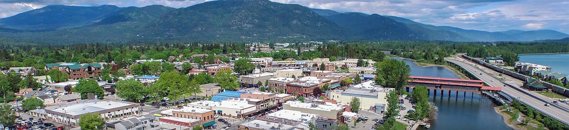 An aerial view of Sandpoint, Idaho, featuring a town layout with buildings, roads, and a river.