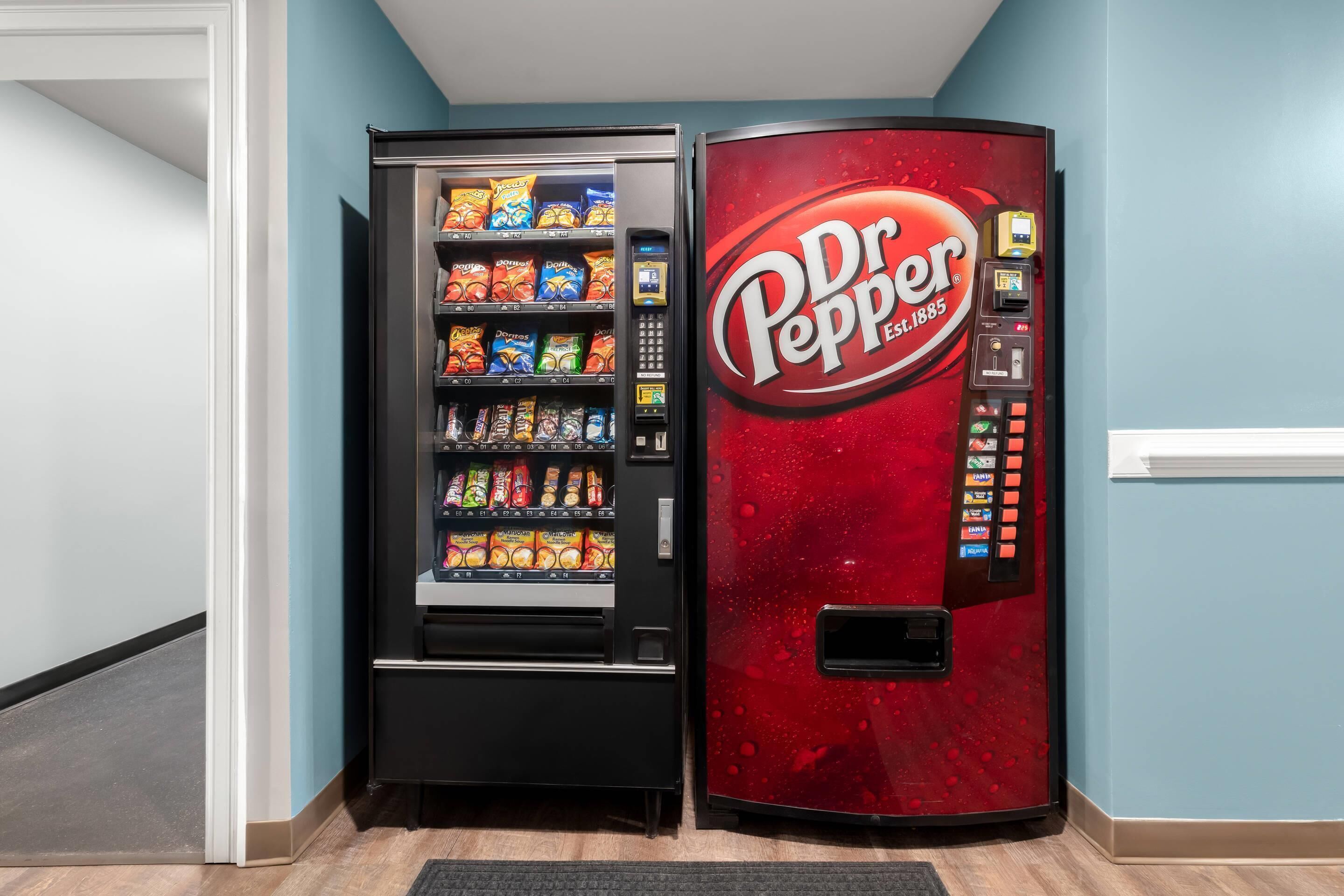 Máquina expendedora con el logotipo de Dr. Pepper y otra máquina expendedora de snacks a su lado.