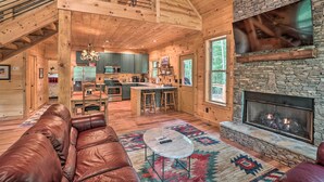 A spacious cabin interior with a stone fireplace, leather sofa, and a dining area. - Peaceful Cabin on 3 Private Acres: Deck & Fire Pit (Blairsville)