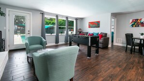 Amplia sala de estar con mesa de fútbol, un sofá y zona de comedor.