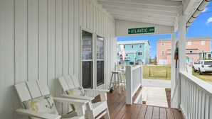 Katettu kuisti, jossa on valkoisia tuoleja ja näkymä Atlantic Boulevardin varrella oleviin taloihin.