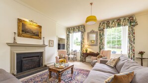 Una sala de estar con chimenea, sofá, sillón y una mesa de centro con adornos.