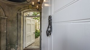 Puerta blanca con manija de metal negro y una lámpara arriba.