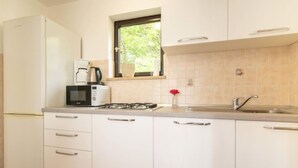 Una cocina moderna con armarios blancos, estufa a gas, microondas y un lavabo.
