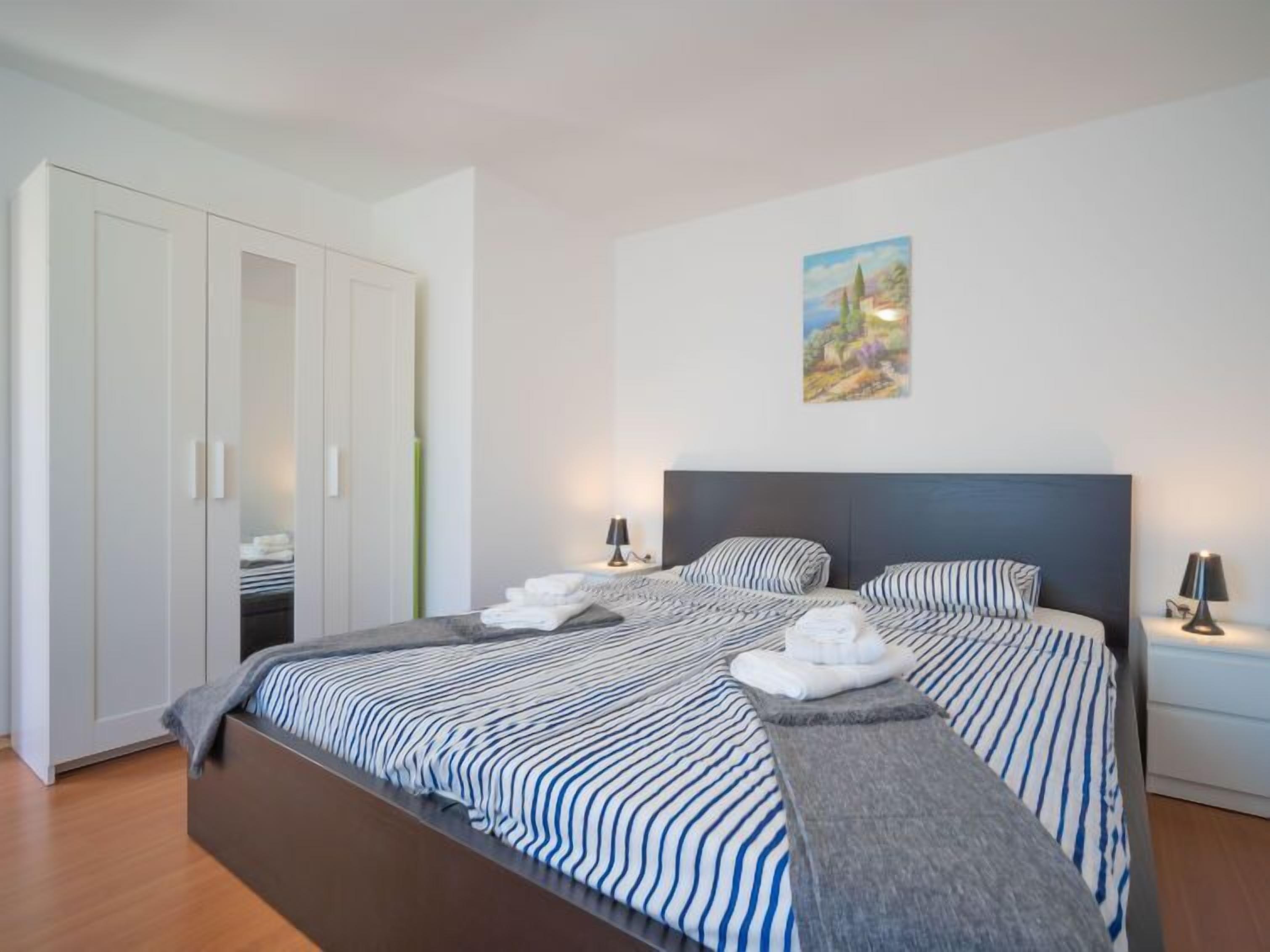 A bedroom with a large bed, a wardrobe, and a painting on the wall.