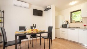 Una cocina moderna con armarios blancos, una mesa de comedor con sillas y un televisor de pantalla plana montado en la pared.