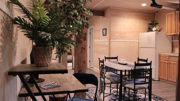 A compact kitchen with wooden cabinets, a refrigerator, and a dining table with chairs. - The best OBX sunsets (Waves)