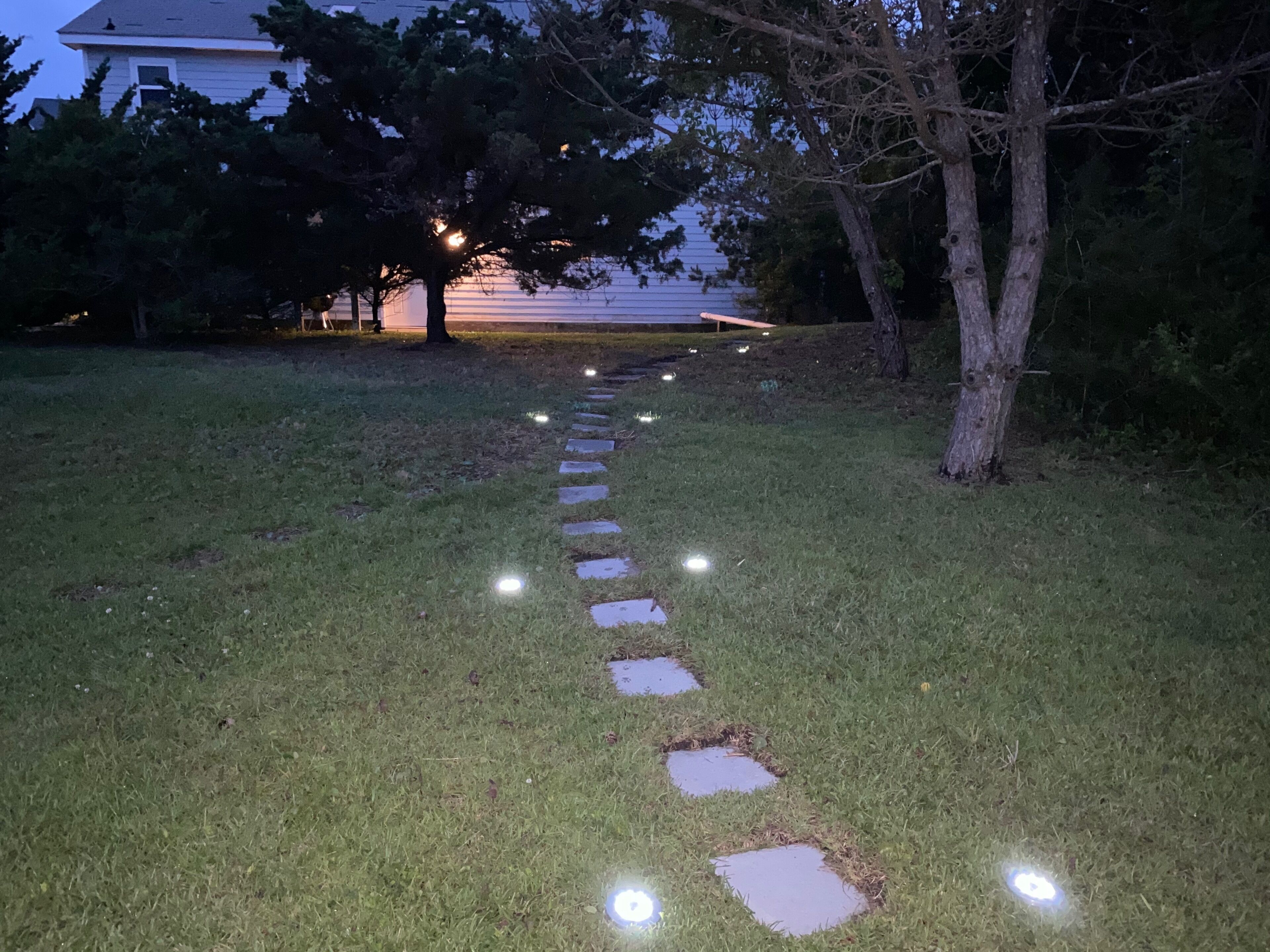 Un sentier extérieur illuminé, avec des pas japonais et des lampes, conçu pour être utilisé la nuit.