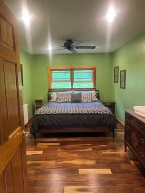 A bedroom with a bed, a ceiling fan, a window, and a dresser.