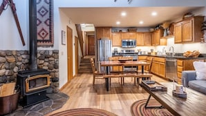 Una cocina acogedora con armarios de madera, una pared de piedra y una estufa de leña.