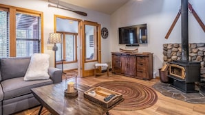 Una sala de estar acogedora con chimenea, un sofá, una mesa de centro y un televisor.