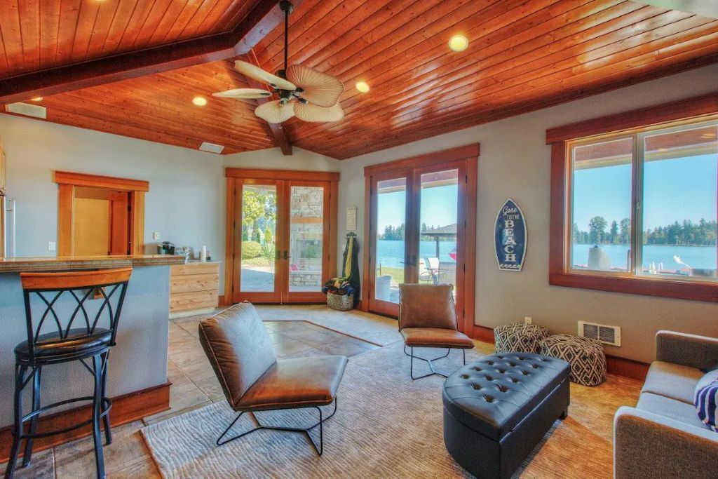 Un'ampia zona living con soffitto in legno, angolo bar e ampie finestre con vista sull'esterno.