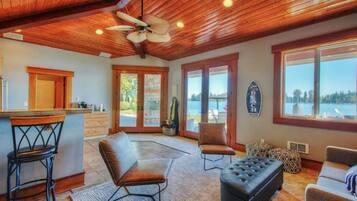 Un'ampia zona living con soffitto in legno, angolo bar e ampie finestre con vista sull'esterno.