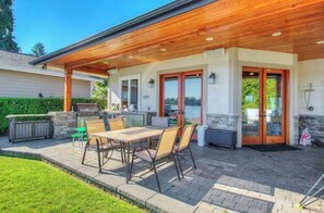 Une terrasse extérieure dotée d’un plafond en bois, d’un barbecue et d’une table avec des chaises.