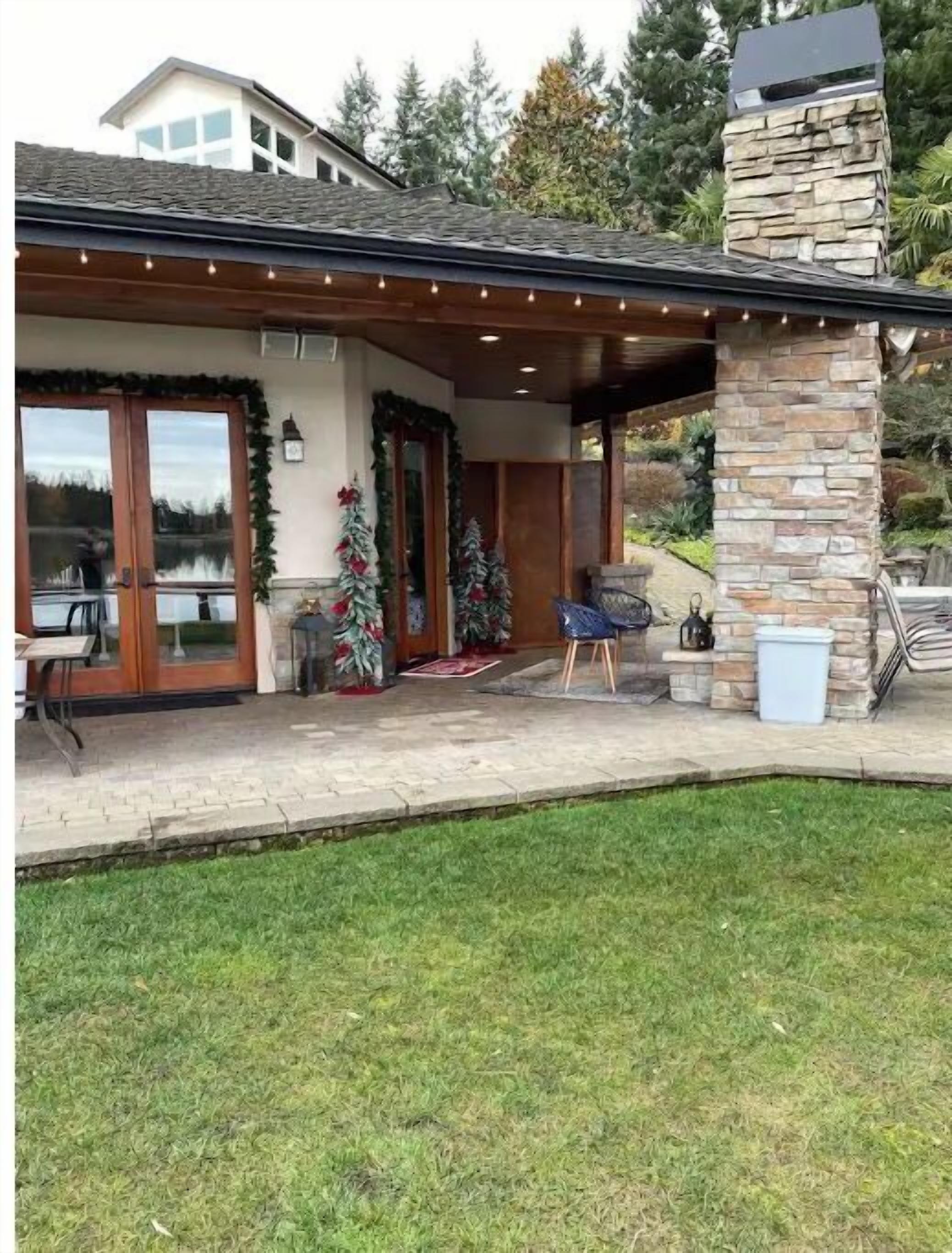A covered patio with stone pillars, a fireplace, and a view of a lake.