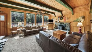 Ein gemütliches Blockhaushaus-Interieur mit einer großen Holzbalkendecke, einem Kamin und einer Sofagarnitur.