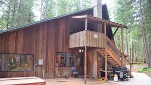 A rustic cabin with a wooden exterior, a balcony, and a staircase leading to a second floor. - The Lodge on Shawnee Trail | Wifi, Hot tub (Packwood)