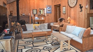 A cozy wooden interior with a fireplace, sofa, and coffee table. - The Lodge on Shawnee Trail | Wifi, Hot tub (Packwood)