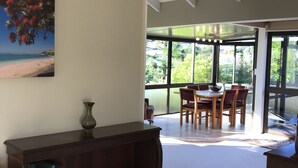 A spacious room with a large window, a dining area with a table and chairs, and a bookshelf filled with books.