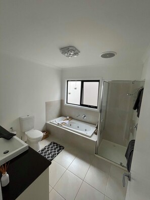 Un bagno moderno con WC, lavabo, vasca da bagno e doccia.