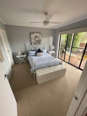 Una camera da letto con un letto, un ventilatore a soffitto, una finestra e vista sull'esterno.