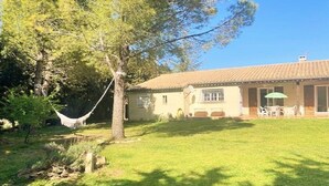 Una casa con tetto in tegole, un'amaca e un patio con sedie.
