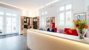 A modern reception area with a wooden counter, a seating area, and a window providing natural light.