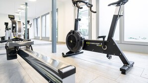 A gym with cardio equipment, including a stationary bike and elliptical machine, and a bench.