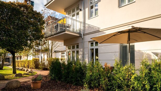 A building with a balcony, a pathway, and potted plants.