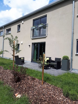 Een modern gebouw met een balkon, terras en een tuinomgeving.