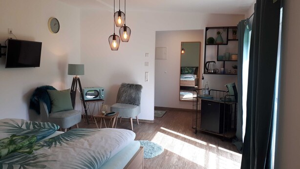 Un dormitorio moderno con cama, escritorio, silla, televisor y espejo.