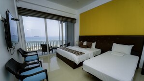 A hotel room with two beds, a TV, a balcony with a view of the sea, and a chair. - Trincomalee Beach Resort & spa (Trincomalee)