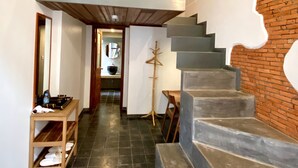 Un intérieur moderne avec un escalier, un banc en bois et une petite table agrémentée d’un miroir.