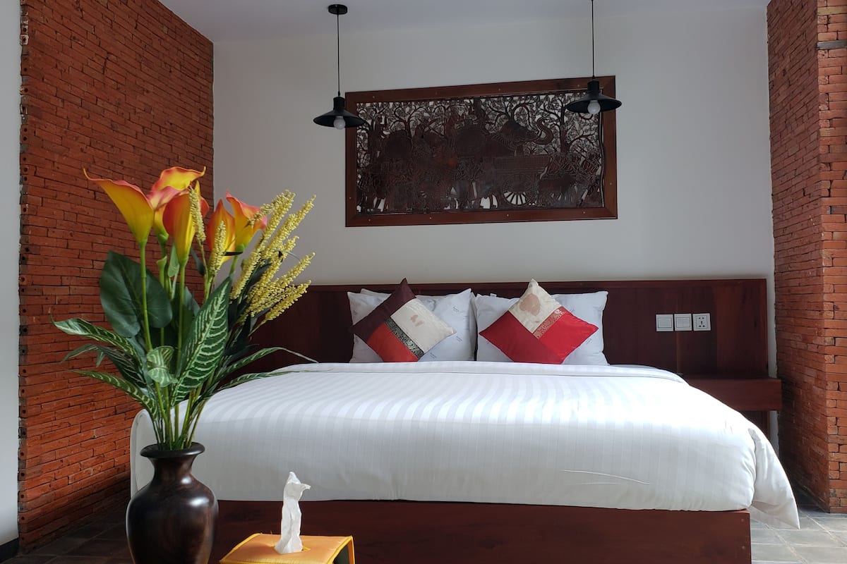 Un dormitorio con una cama, un adorno en la pared y un jarrón con flores.