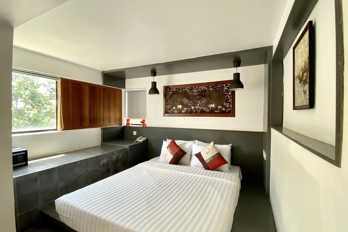 Un dormitorio moderno con una cama grande, un banco empotrado, un ventanal con vistas y un elemento decorativo en la pared.