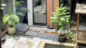 Un immeuble à plusieurs étages doté d’une cour intérieure aménagée avec une petite piscine, des plantes en pot et des sièges d’extérieur.