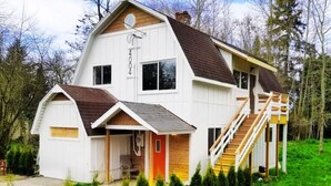 A two-story house with a steeply pitched roof, a front porch, and a staircase leading to the upper level. -  Updated  farm style Apt.  w/ loft minutes from Airport and Seattle (Tukwila)