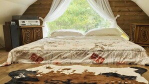 A bedroom with a bed, a wooden headboard, a window with curtains, and a cowhide rug. -  Updated  farm style Apt.  w/ loft minutes from Airport and Seattle (Tukwila)