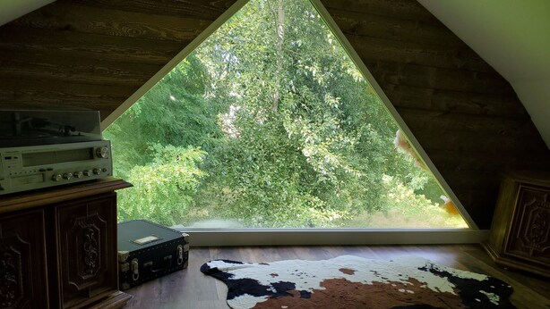 An attic room with a large triangular window overlooking a forest. -  Updated  farm style Apt.  w/ loft minutes from Airport and Seattle (Tukwila)