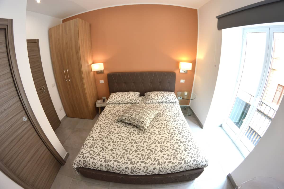 Une chambre à coucher avec un lit, deux lampes de chevet, une armoire et une fenêtre donnant sur un beau paysage.