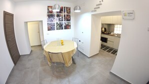 Een eetgedeelte met een ronde tafel, stoelen en een wandlamp.