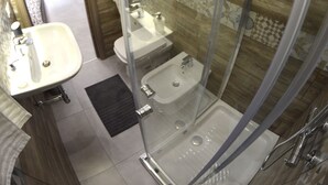 Een moderne badkamer met een douchecabine van glas, een ronde spiegel en een wastafel met twee kommen.