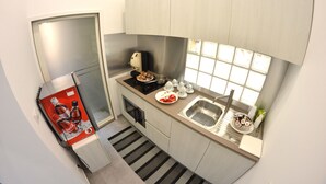 Een kleine keuken met een koelkast, een wastafel en een raam.