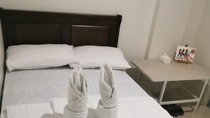 A neatly made bed with white linens and two towels folded on top. - Flip Flops Hostel (Pasay)