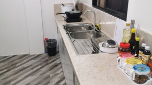 A compact kitchen with a sink, stove, and various condiments. - Flip Flops Hostel (Pasay)