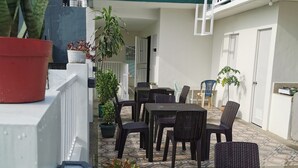 An outdoor patio area with a patterned tile floor, wicker furniture, and potted plants. - Flip Flops Hostel (Pasay)