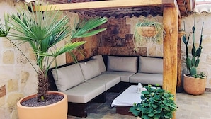 Un coin salon avec un banc rembourré, une plante en pot et un pot suspendu.