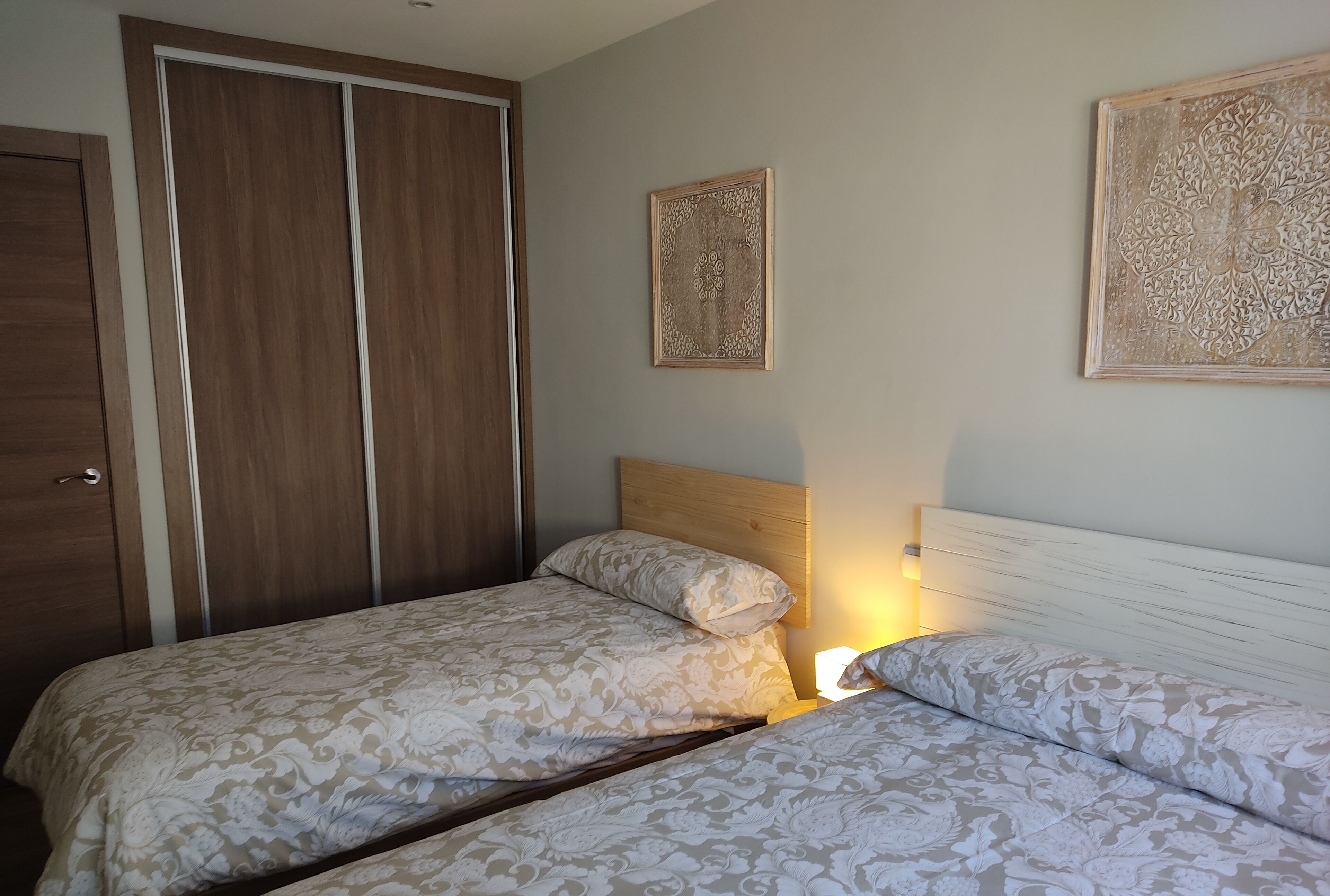 Een slaapkamer met twee bedden, een kledingkast en decoratieve wanddecoratie.