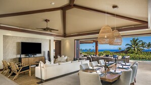 A spacious living area with a large flat-screen TV, comfortable seating, and a dining table set for six. - Luxury 5BR Kulanakauhale Estate 3558 at Hualalai – Infinity Pool & Ocean Views (Kailua Kona)