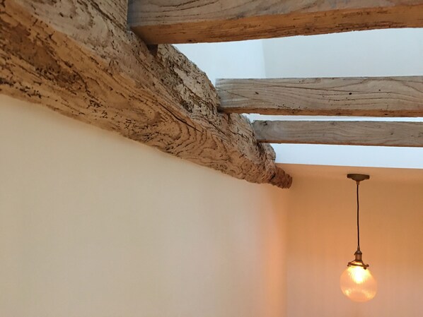 A ceiling with exposed wooden beams and a single hanging light fixture.